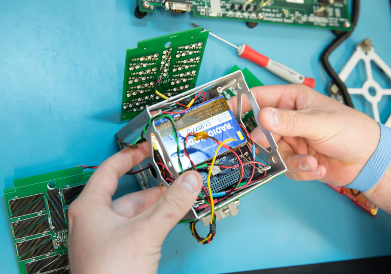 Photo of a student's hands holding the EagleSat-1 CubeSat.