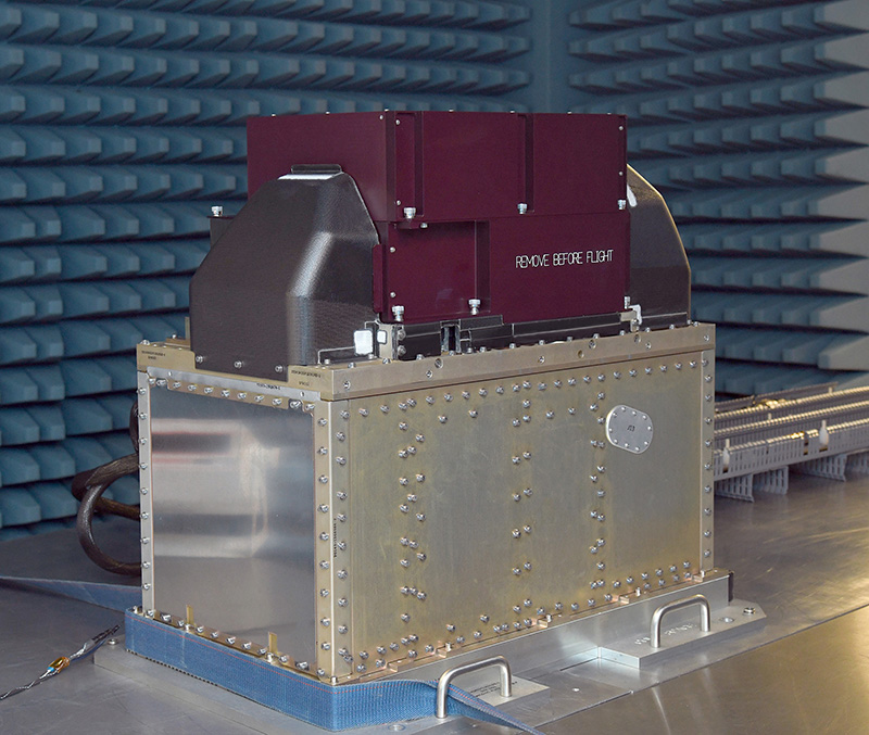 The ATMS instrument sits on a metal table inside the electromagnetic interference testing chamber while undergoing testing.