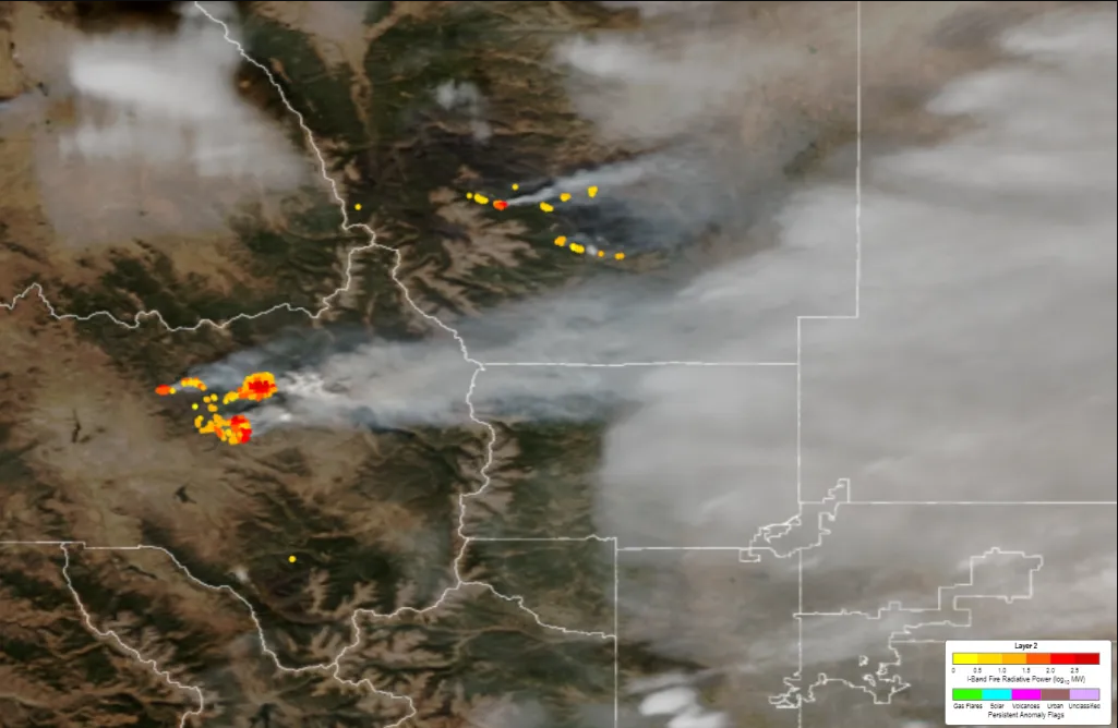Overlaid on top of a true color satellite image of Colorado is a cluster of yellow, red and orange dots on the left side that give off a massive cloud of smoke that covers nearly the rest of the image.