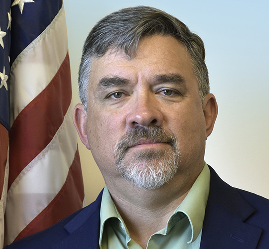 Eric Kihn in front of an american flag.