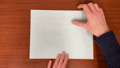 Animation of hands folding a piece of paper in half.