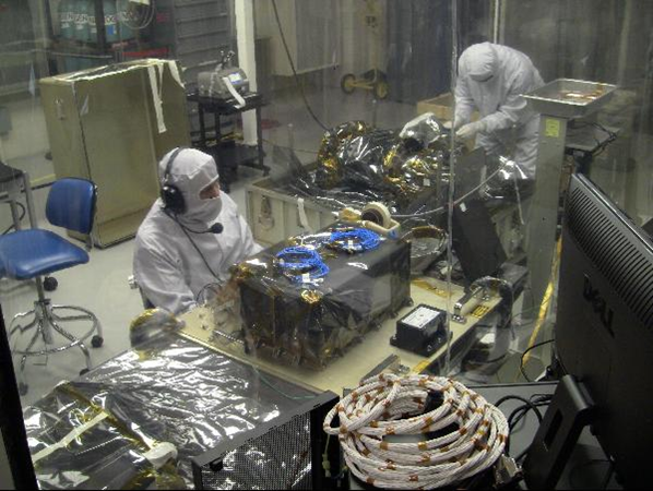 A technician in protective gear sits at a desk 