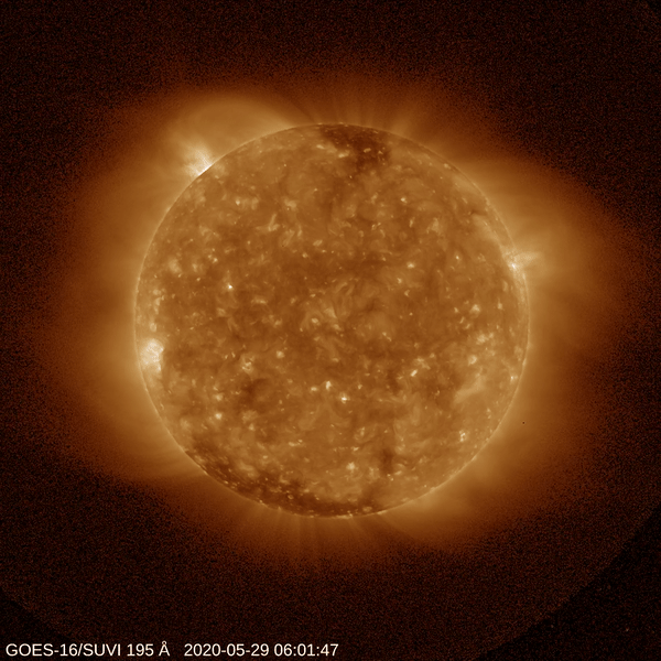 Orange sphere of the sun against black background with yellow/orange protuberance showing the flare in the top left. 