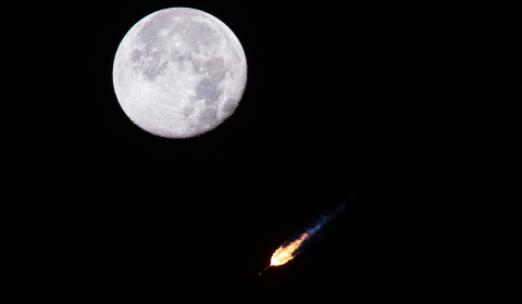 Night photo of a rocket blast next to the Moon.