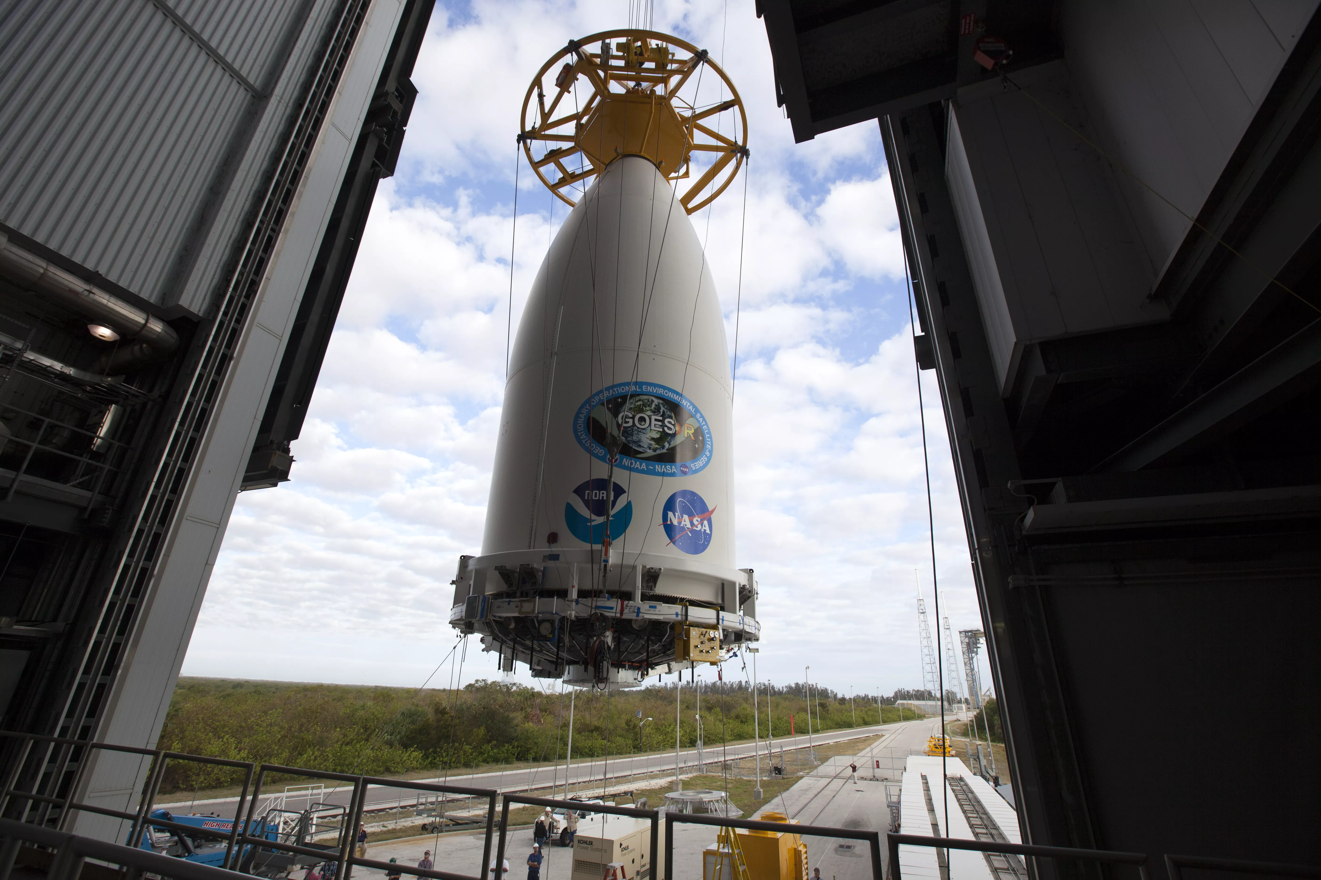 A crane lifts the GOES-R payload fairing for mating to the Atlas V upper stage.