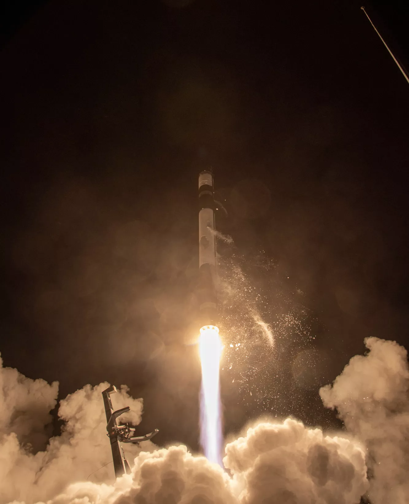 The rocket carrying General Atomics’ GAzelle satellite lifts off, illuminating the dark sky behind it.