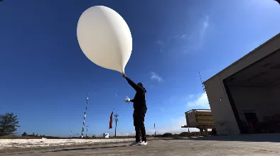 Person about to release a weather balloon outdoors.