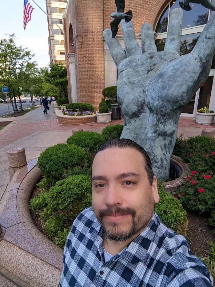 Joseph Smith standing in front of the hand sculpture in front of the NOAA Headquarters office in Silver Spring, MD
