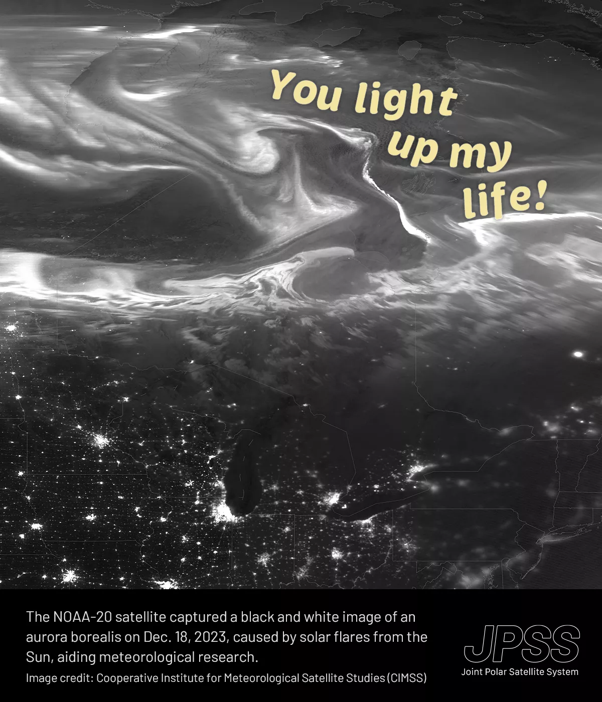 This Valentine's Day card features a black and white satellite image of part of the Northern Hemisphere, showcasing a dramatic natural light display of an aurora borealis. In the upper right-hand corner, playful script in light yellow states “You light up my life!” Beneath this phenomenon, the city lights of the United States can be seen as intricate networks of glowing dots. At the bottom of the card, there's a caption that reads, “The NOAA-20 satellite captured a black and white image of an aurora boreali