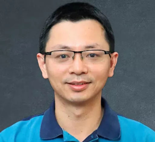Qiusheng Wu Smiling in front of a grey screen.