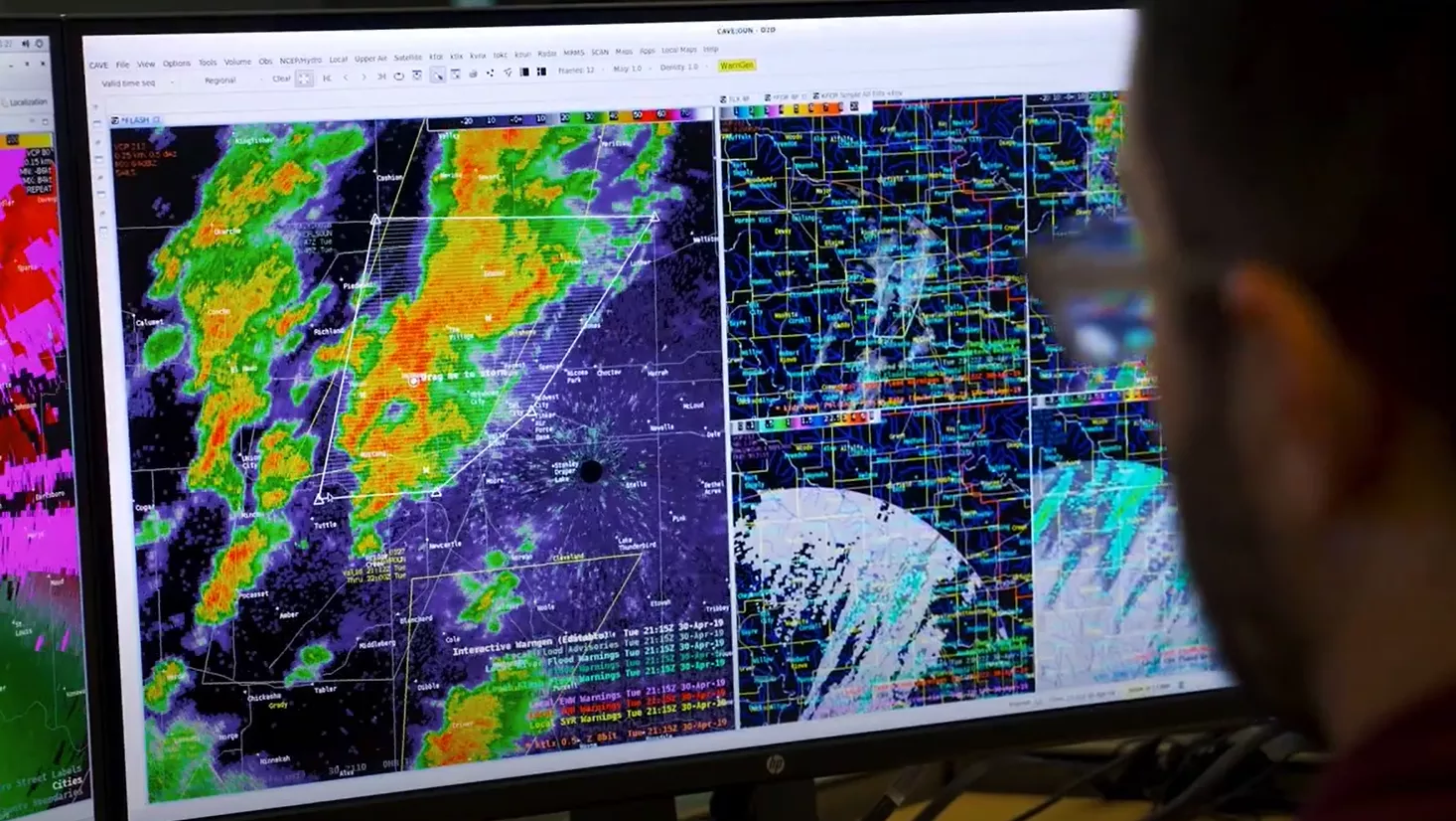 A meteorologist analyzes severe weather data on an AWIPS workstation, displaying radar imagery, storm warnings, and meteorological maps for forecasting.