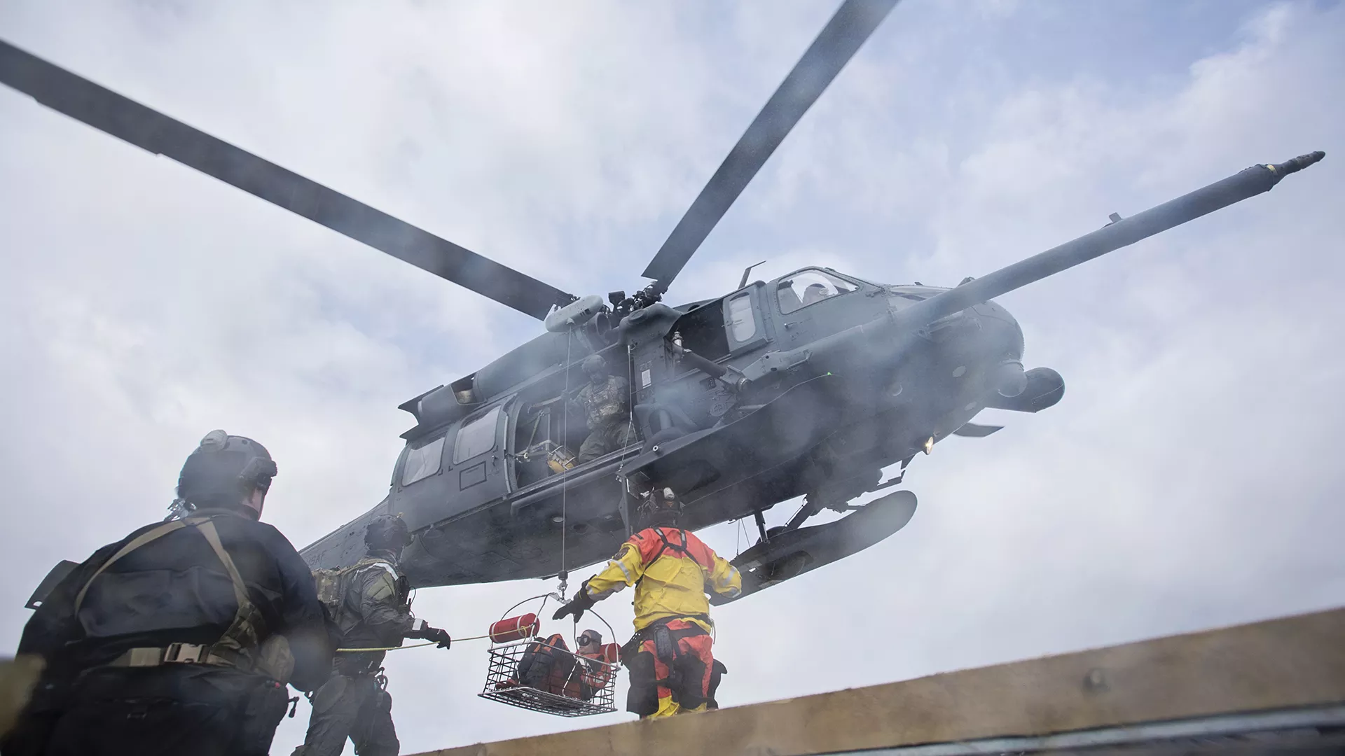The coastguard rescuing someone hanging in a basket from a helicopter