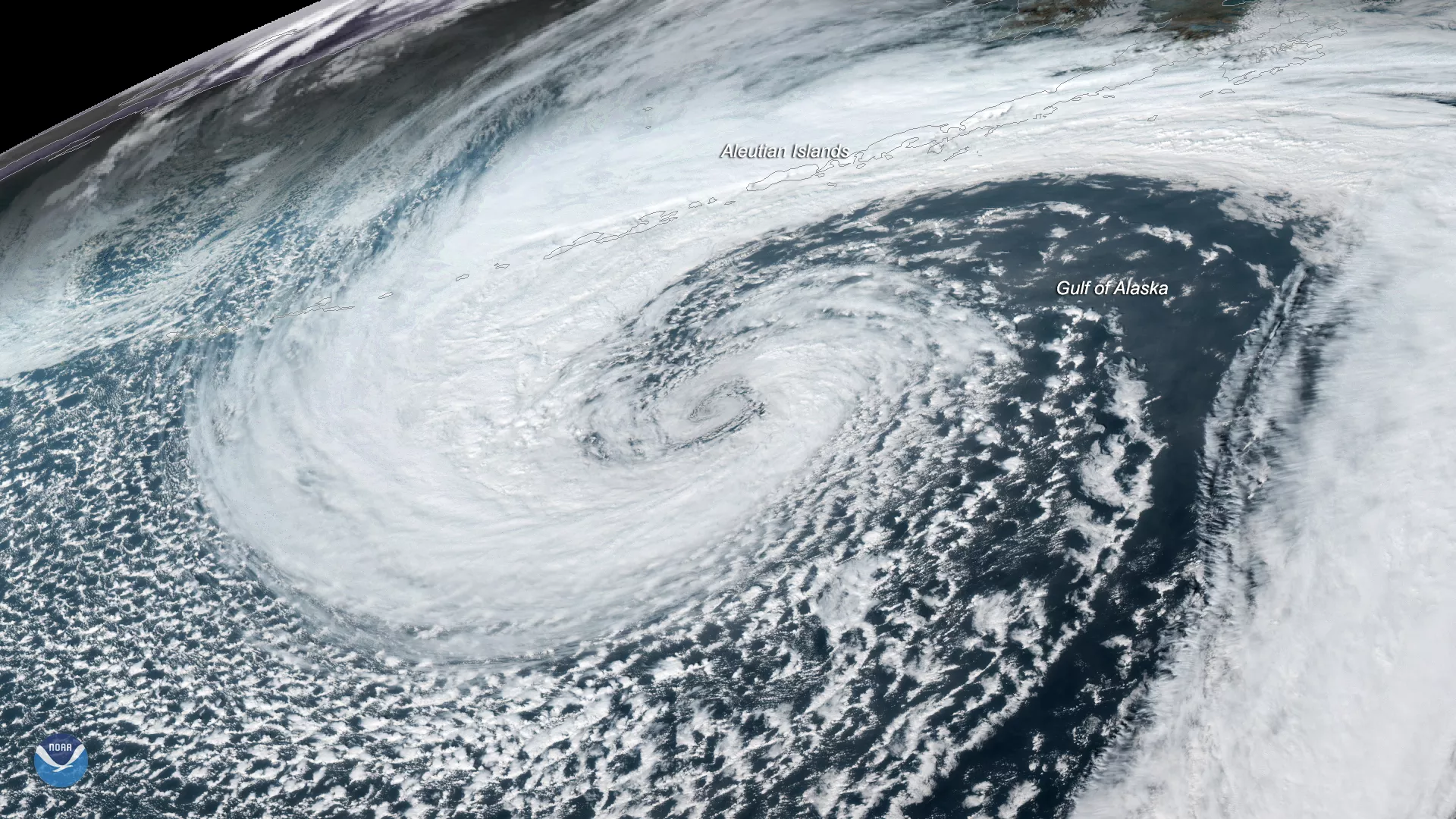 Large, white, swirling low pressure system cloud that looks like a reverse comma over the Gulf of Alaska and Aleutian Islands. 