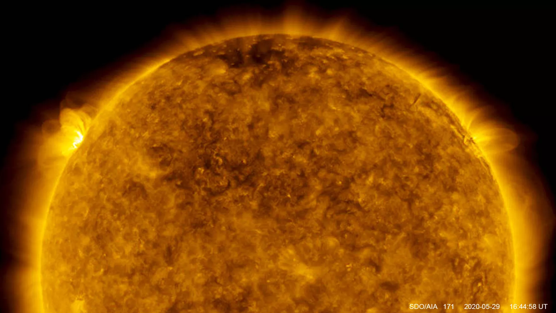 Orange sphere of the sun against black background with yellow/orange protuberance showing the flare.