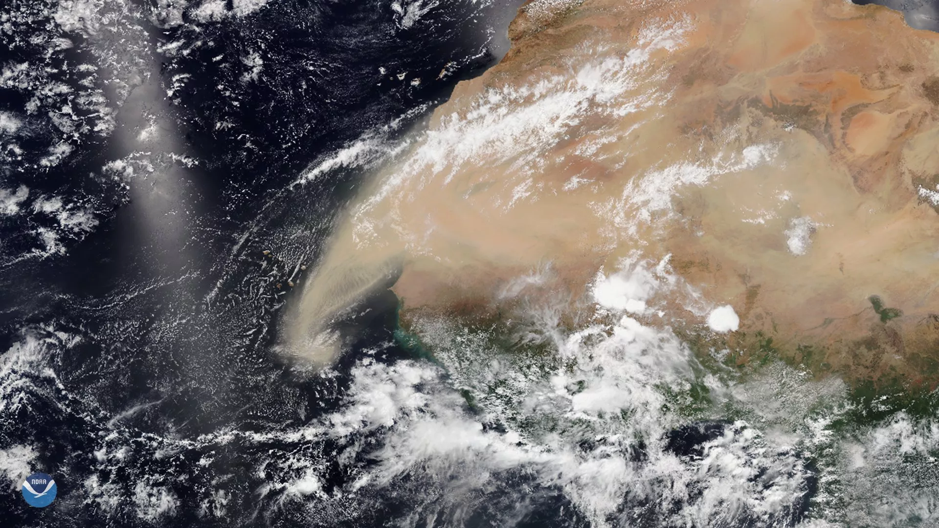 Large brown dust plume mixed with white clouds is seen over Western Africa and extending over the Atlantic Ocean.