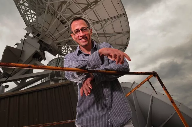 Image of expert Jim Kossin next to a satellite dish. 