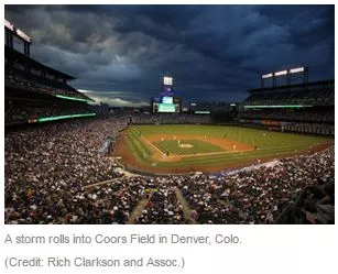 Image of a baseball Stadium with dark clouds overhead. Text reads: A storm rolls into Coors field in Denver, CO.