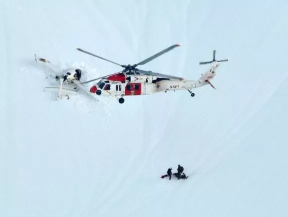Photo of a SARSAT rescue, with a plane flying over snow and stranded hikers.