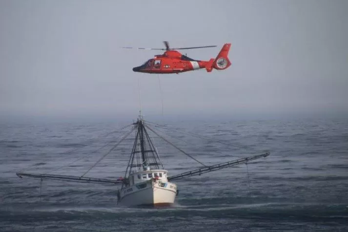 Image of a helicopter rescuing a person in the sea.