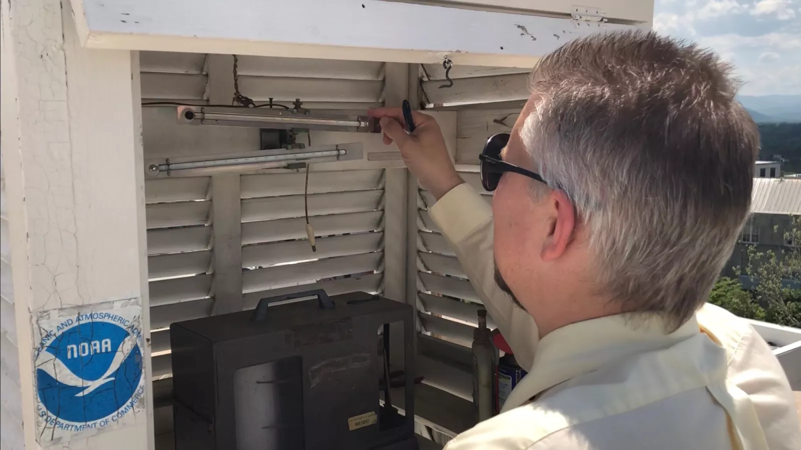 A NOAA employee resets the index on a pair of minimum/maximum thermometers in a NOAA weather station.
