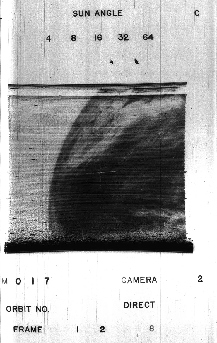 Grainy black and white image from space, showing black sea and white/gray swirling clouds. 